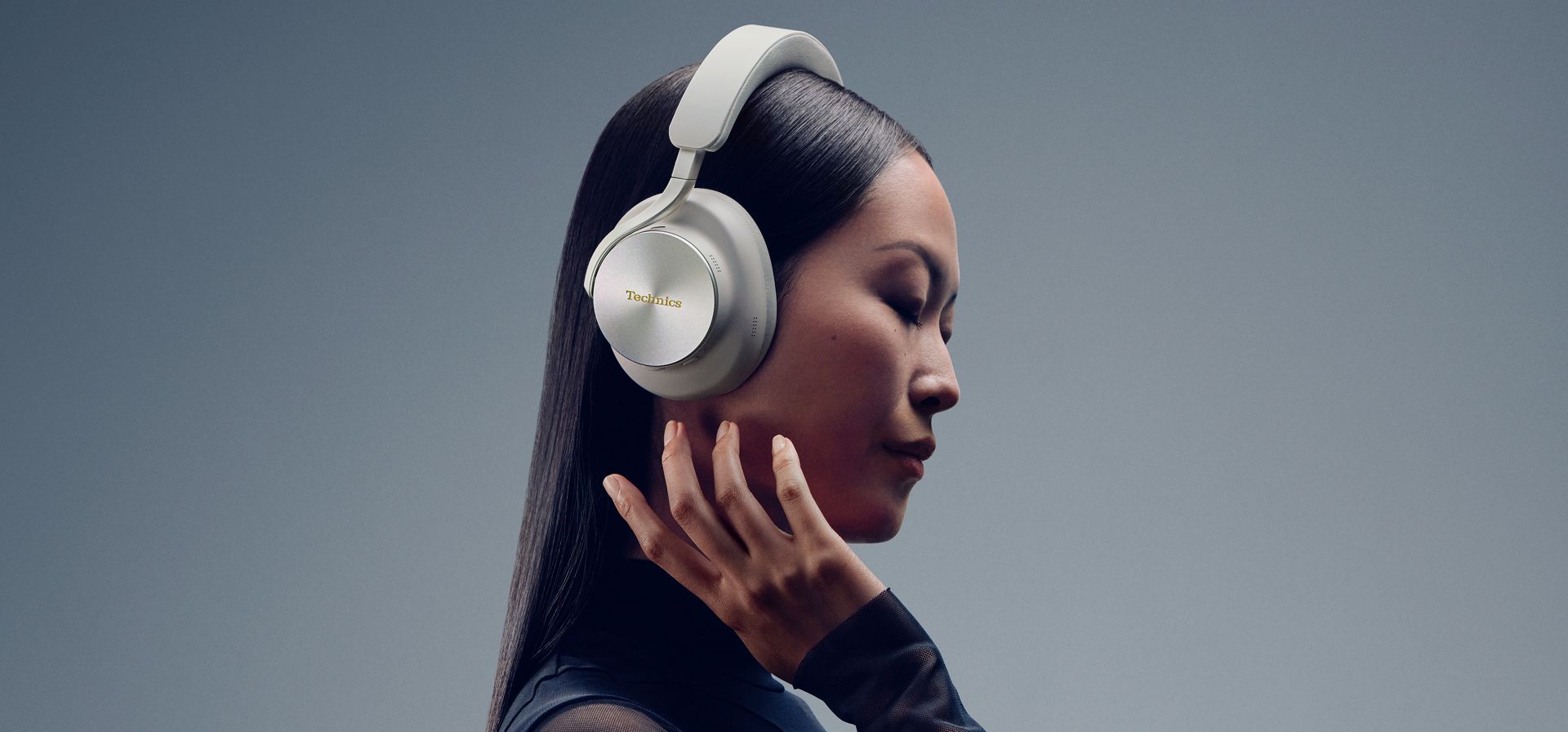 Technics EAH-A1000E-S Technics EAH-A1000 bezprzewodowe słuchawki z adaptacyjną redukcją szumów ANC (parowanie wielopunktowe Bluetooth, LDAC, do 45H pracy z ANC), srebrne 6 Kobieta nosząca słuchawki Technics EAH-A1000 prezentuje nacisk na szczegółowy, wciągający dźwięk.
