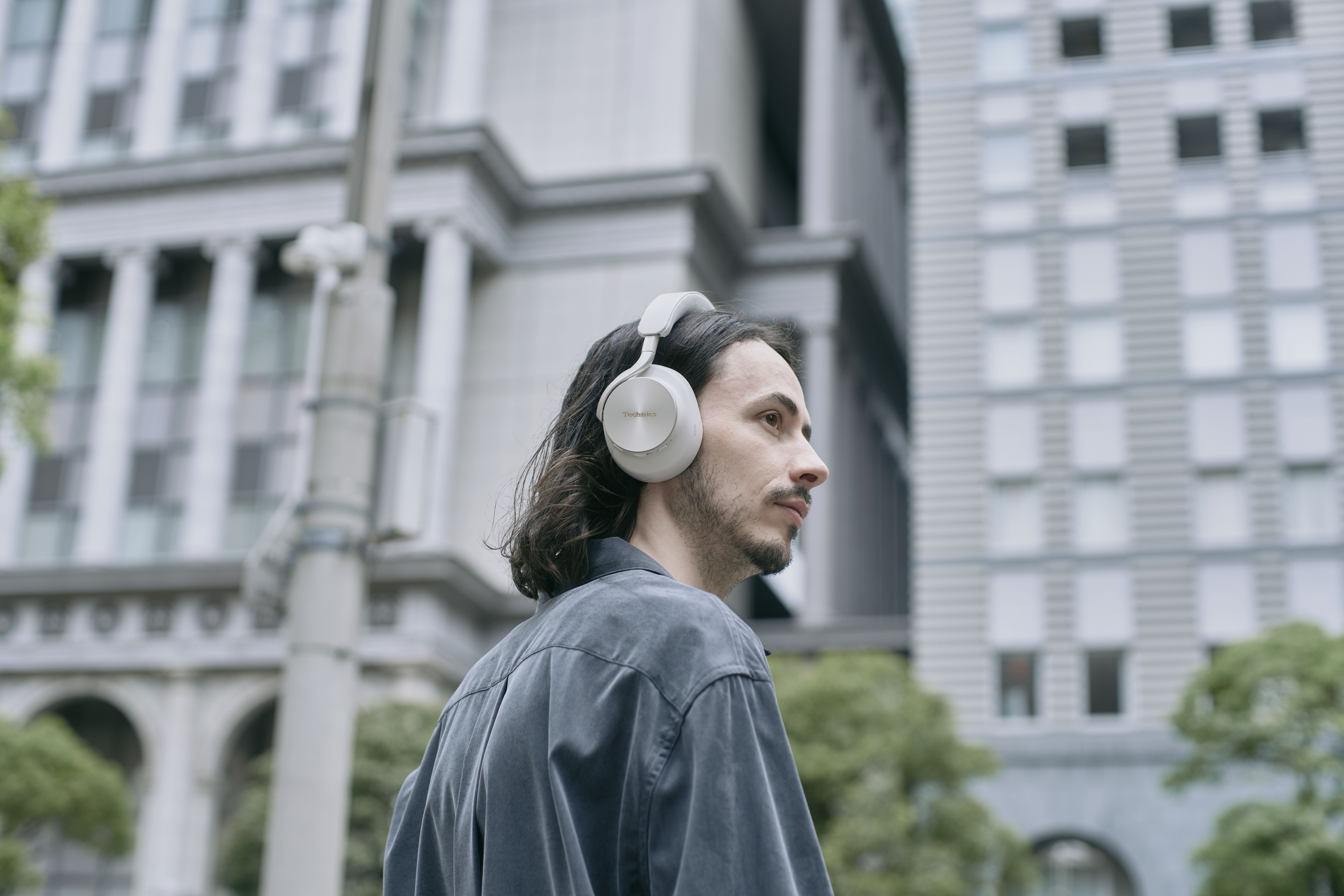 Technics EAH-A1000E-S Technics EAH-A1000 bezprzewodowe słuchawki z adaptacyjną redukcją szumów ANC (parowanie wielopunktowe Bluetooth, LDAC, do 45H pracy z ANC), srebrne 42 Mężczyzna w słuchawkach nausznych marki Technics w mieście.