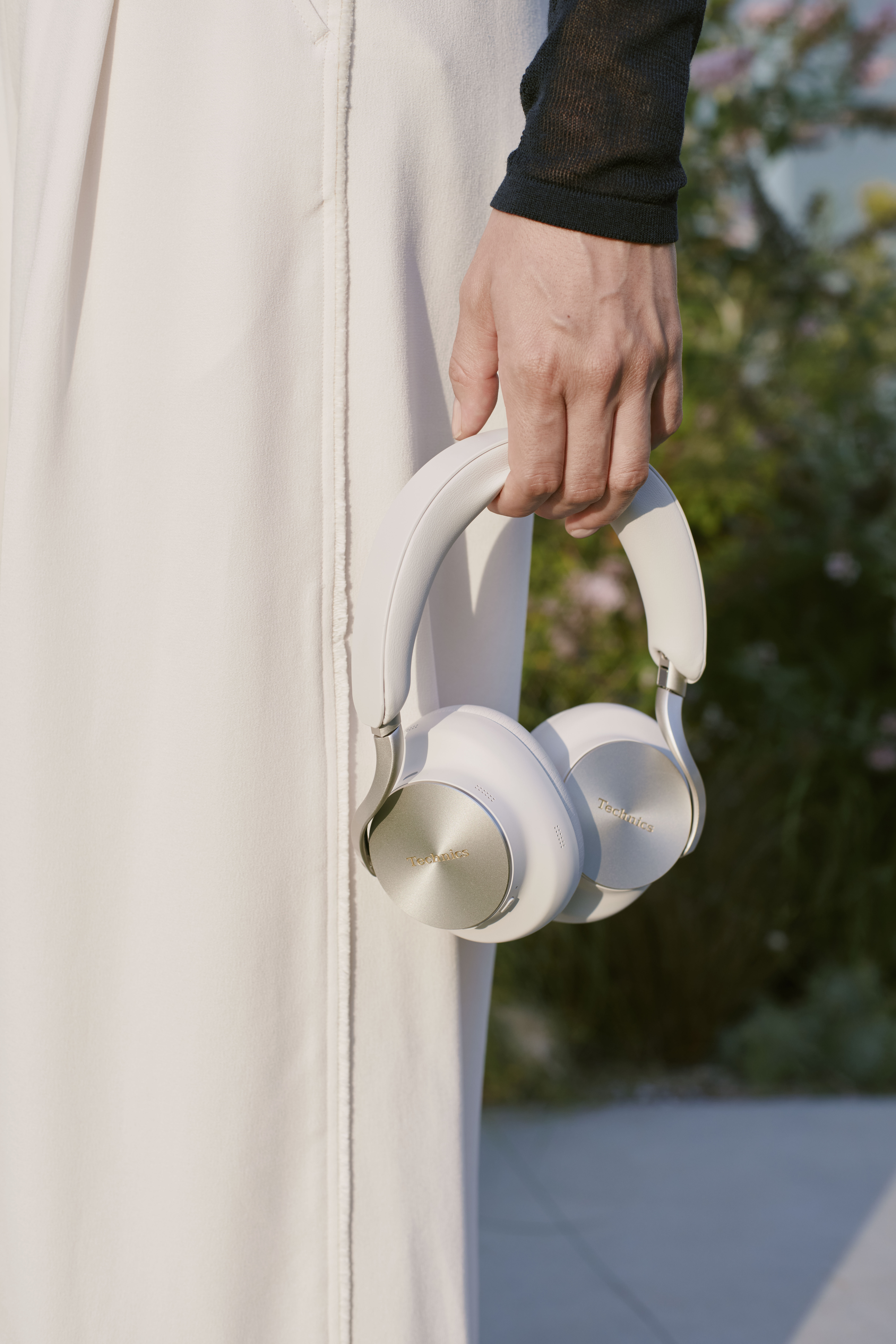 Technics EAH-A1000E-S Technics EAH-A1000 bezprzewodowe słuchawki z adaptacyjną redukcją szumów ANC (parowanie wielopunktowe Bluetooth, LDAC, do 45H pracy z ANC), srebrne 46 Osoba niosąca beżowo-szare słuchawki nauszne marki Technics za pałąk.